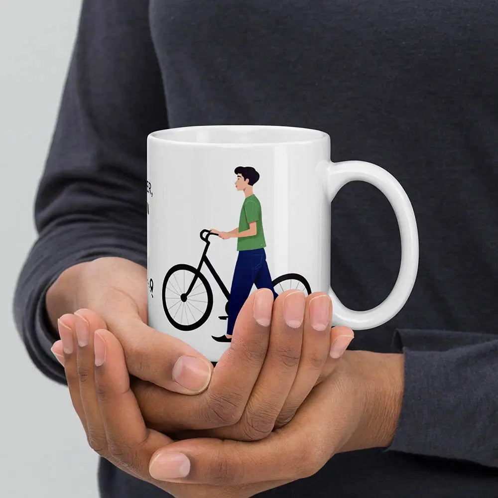 Eine weiße Tasse mit einem Fahrrad Motiv und einem Herren gehalten in zwei Händen einer Person im Hintergrund