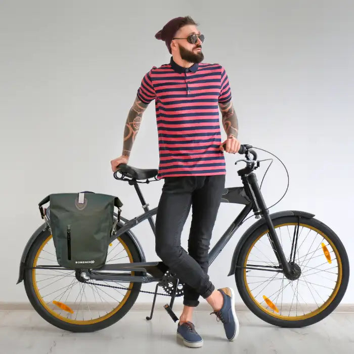 Mann mit blauer wasserdichten Fahrradtasche, lässig gegen sein Fahrrad gelehnt.