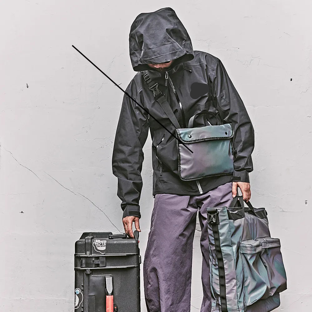 Mann schwarz gekleidet mit vielen Taschen und reflektor
