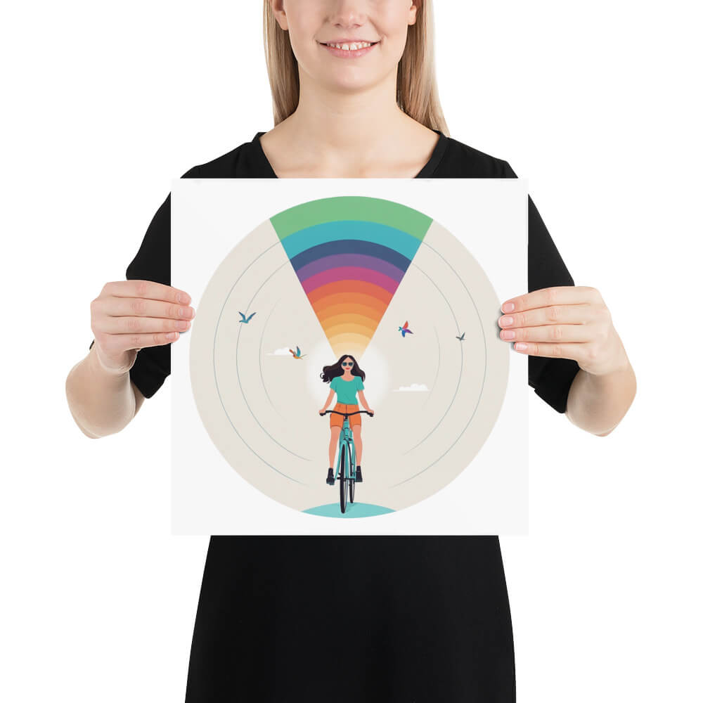 Das Bild zeigt eine Person, die ein quadratisches Poster hält. Auf dem Poster ist eine stilisierte Illustration einer Frau mit dunklen Haaren zu sehen, die mit einem Fahrrad fährt. Über ihr entfaltet sich ein leuchtendes Regenbogenmuster in einem strahlenförmigen Design. Um sie herum fliegen Vögel, während der Hintergrund eine helle, minimalistische Himmelsszene mit sanften Wolken darstellt. Die Illustration zeichnet sich durch klare Linien, harmonische Farben und eine moderne, grafische Ästhetik aus.