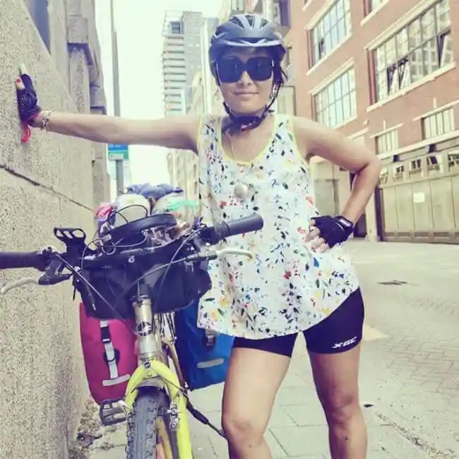 Frau mit Fahrrad und pinke Radtasche bei einer Cycling Tour in der Stadt.