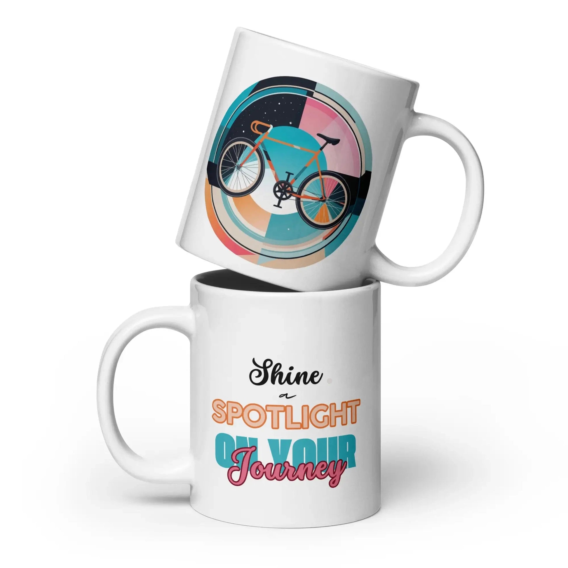 Weiße glänzende Kaffeetasse mit 20 oz Fassungsvermögen, schlichte und elegante Vorderansicht. Weiße Kaffeetasse mit einem bunten Fahrradmotiv auf der einen Seite und dem inspirierenden Spruch „Shine a Spotlight on Your Journey“ auf der anderen Seite.