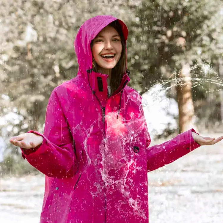 Frau im Regen mit Wasser und pinker Regenjacke und Ärmeln und Kapuze