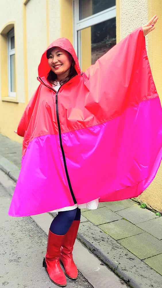 Frau mit rot pinkem Regenponcho mit Reißverschluss