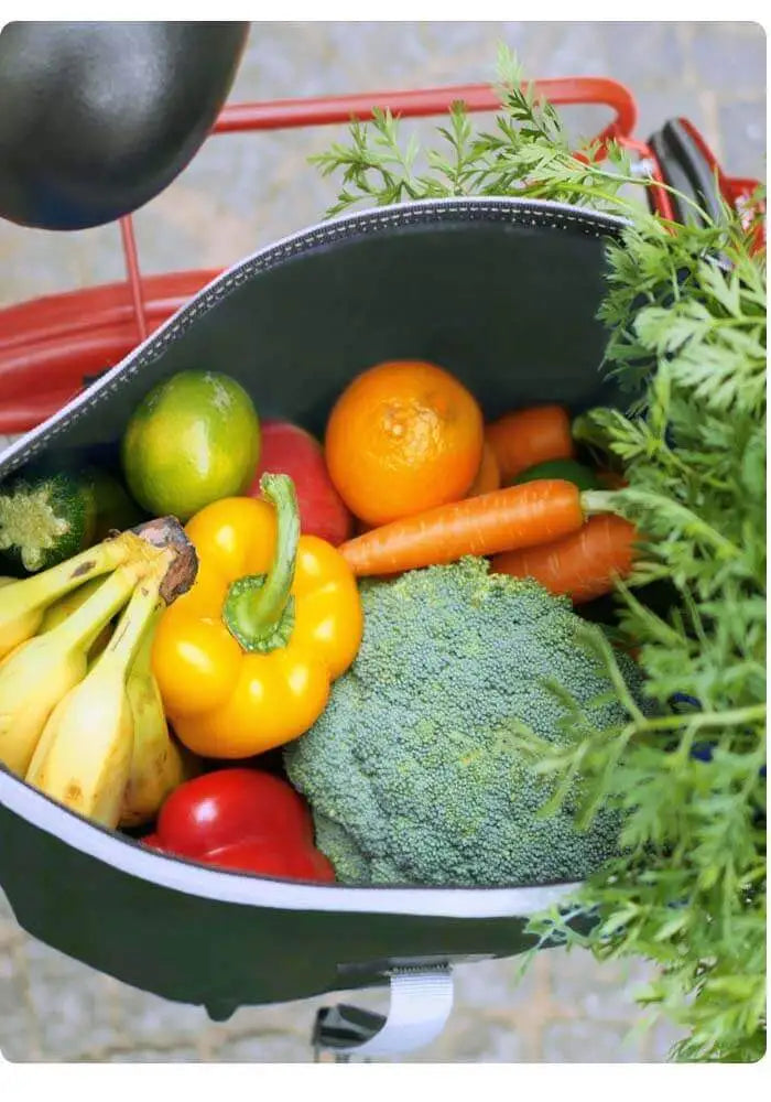 Gepäckträgertasche am Hinterrad offen mit Gemüse und Einkauf innen. Fotografie von oben.