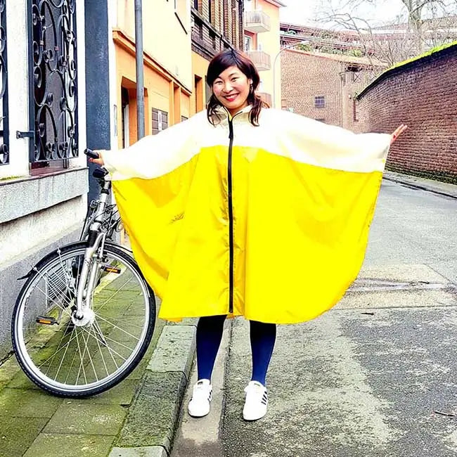 Frau mit Regenponcho senfgelb Asiatin Fahrrad Cape