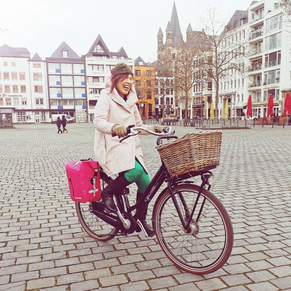 Schicke rosa Fahrradtasche Damen mit großen Volumen. Glückliche Frau mit Rad in der Stadt Köln.
