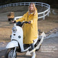 Regenmantel Fahrrad in gelb und extra weit getragen von einer Frau sitzend auf dem Roller. Der weite Regenmantel ist geeignet für Fahrradfahren, Rollerfahren und Mopedfahren. Der Fahrradregenmantel im A-Form ist für Damen sowie Herren elegant und schön zu tragen.